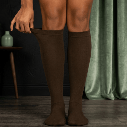Bas de compression Serena™ noir et vert sauge, porté sur des jambes croisées, avec un fond modifié.